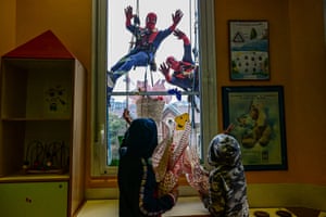 Two people wearing Spiderman costumes are seen dangling outside a hospital window