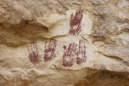 Red handprints on a rock wall.