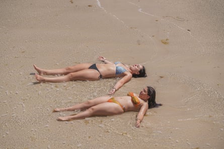 Two young women lie in shallow water cooling down