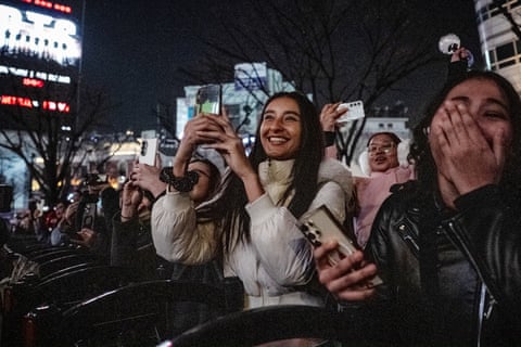 Fans of K-pop boy band outside at night watch the show