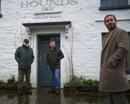 Three men standing outside a pub on a rainy day, all wearing jackets