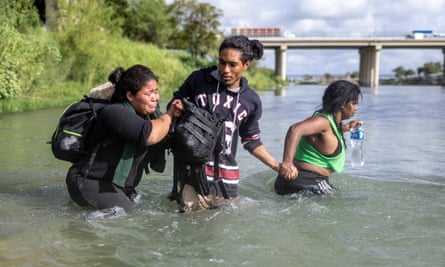 Three people, one crying, waded waist-deep in the river, holding hands.