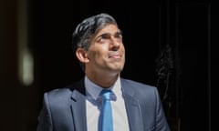 Rishi Sunak wears a navy suit and lighter blue tie and looks up towards the sky