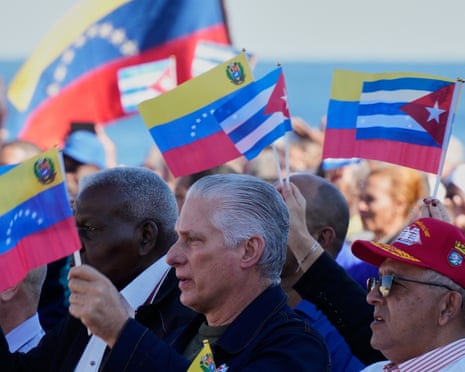 The Cuban president stands among a crowd of people holding Cuban and Venezuelan flags
