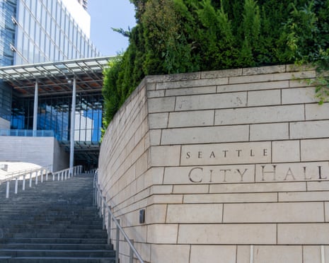 Limestone wall with Seattle City Hall carved into it, alongside tall row of stairs leading to glass building.