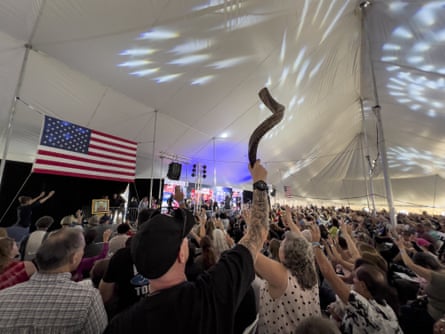 A man holds up a shofar as the audience prays inside a tent during the ReAwaken America tour at Cornerstone Church in Batavia, New York, on 12 August 2022.