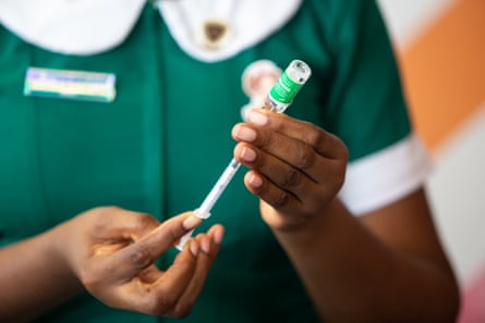 A nurse draws a Covid vaccine into a needle from a vial.