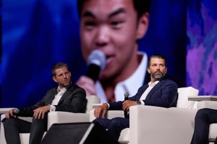 two men in suits sit on stage