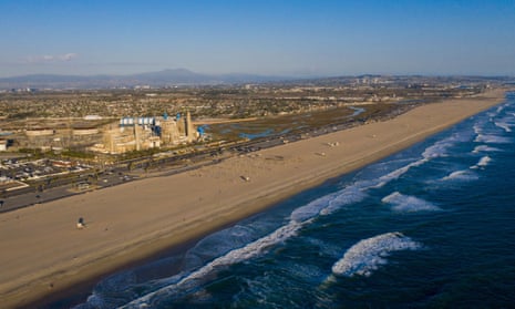 An aerial view of a beach in southern California. A power station can be seen at the left with a swath of empty swampy land next to it.