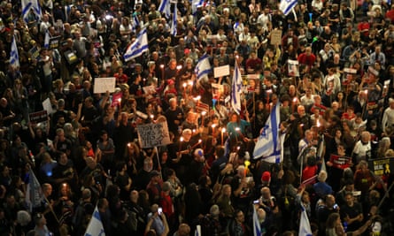 A large crowd of protesters with placards and Israeli flags march through Tel Aviv