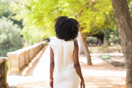 Young woman wearing a white dress walking in park (posed by a model)