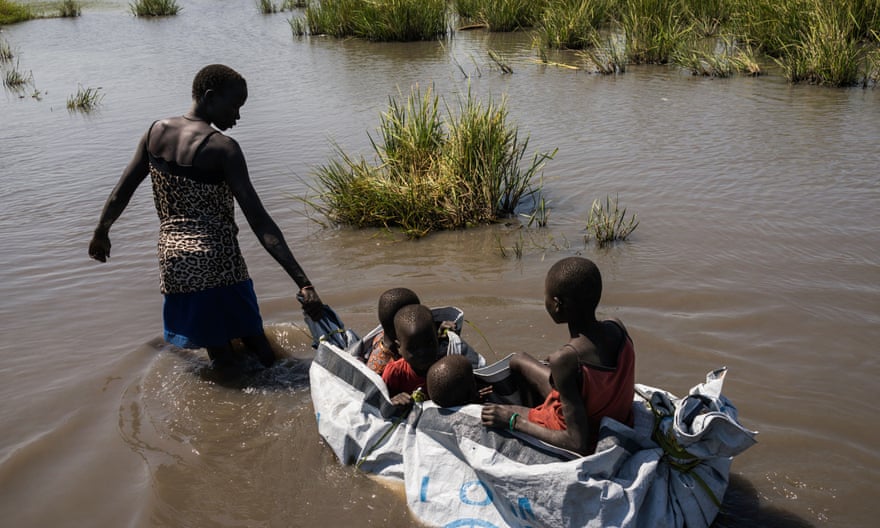 A woman pulls her children with a homemade raft built out of plastic sheeting after receiving a food distribution in Unity State, South Sudan.