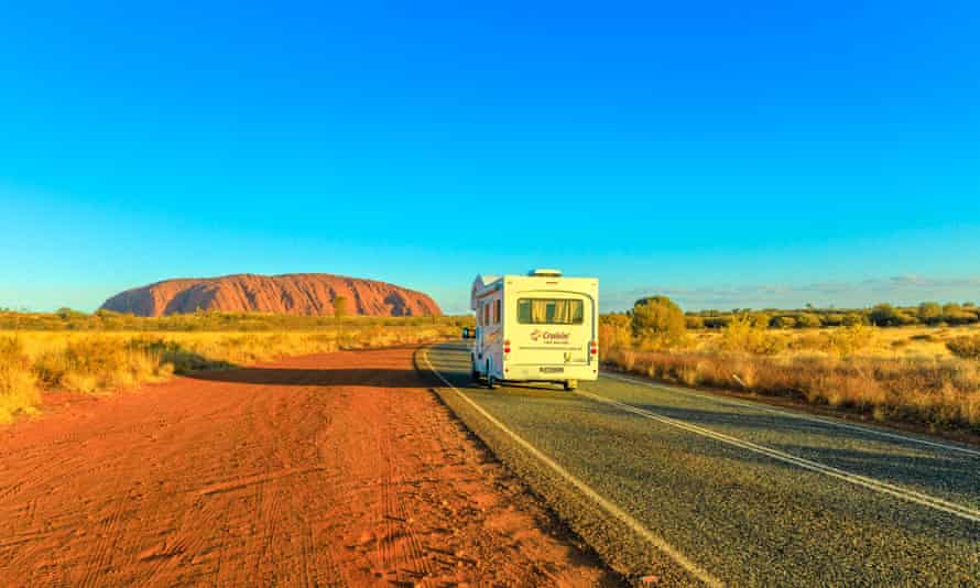 Camper van driving on the road leading to Uluru