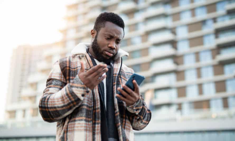 Frustrated young man using phone.Unhappy African American man looking at phone.