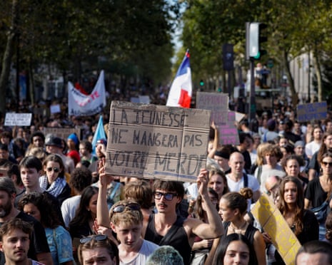 A person hold a placard reading in French "Youth won't eat your shit" during a demonstration part of a nationwide day of action in Paris.