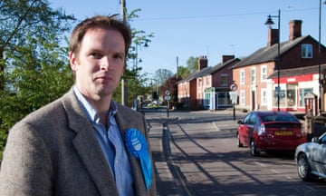 Dr Dan Poulter arrives early to vote at the 2010 general election: he is seen in a village street on a sunny day and is wearing a tweed jacket and blue shirt with a blue Conservatives rosette on his lapel