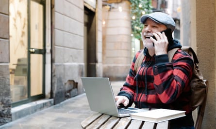 A man on the phone sitting at street cafe with a laptop in Barcelona, Spain