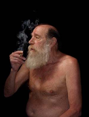 Lawrence Weiner, with grey beard, smokes and gazes off to the side