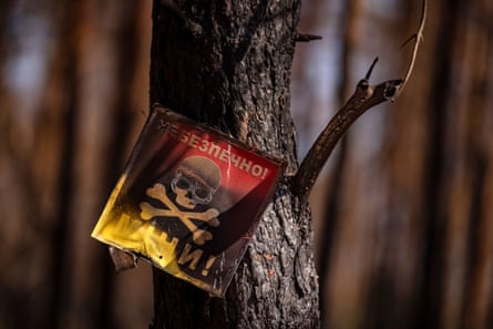 A fire-damaged mine warning sign with a skull and crossbones on a tree