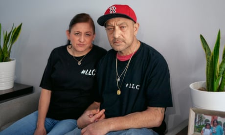 A man and a woman sit indoors with a portrait of a young man above them