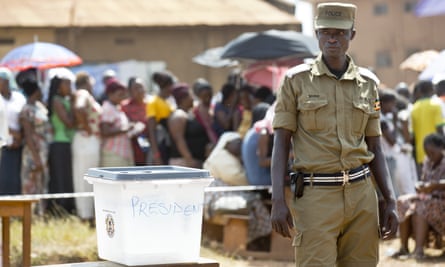 A police officer guards by an empty ballot box at a polling station in Kampala, where five hours after voting was due to start no voting papers had yet arrived.