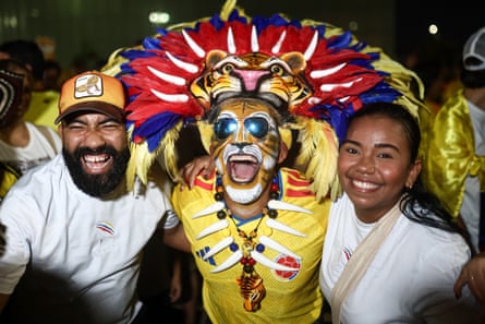 Two people stand next to someone wearing a tiger mask