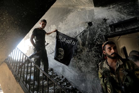 A member of the Syrian Democratic Forces with a black Isis flag found during the fighting with Isis fighters in Raqqa, Syria, 14 August 2017.