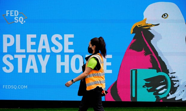 An essential worker walks past a ‘Please Stay Home’ sign on the first day of a five-day Covid lockdown in Melbourne