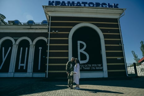 Tetiana and Oleksandr pose for a photo outside a railway station in Kramatorsk