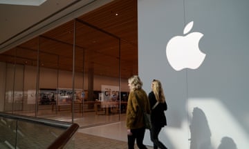 Two people walk by store with silver panels and white Apple logo
