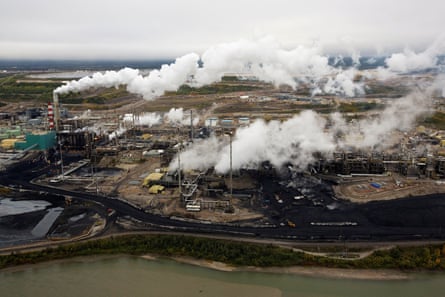 smoke coming from processing plant on edge of sludgey river