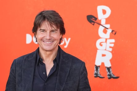 Tom Cruise smiles in a black suit at the