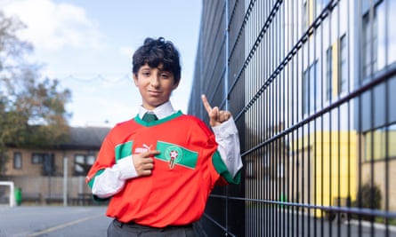 Badr Riane wearing a red-and-green Morocco shirt over his school uniform and standing in a playground