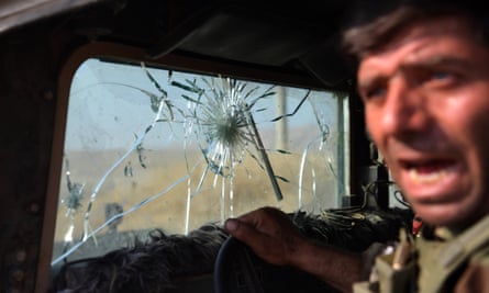A Kurdish peshmerga fighter leans out of his military vehicle which has taken several direct hits from Isis snipers near Mosul