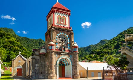 The colourful Soufrière church in Dominica, with green hillside and blue sky behind