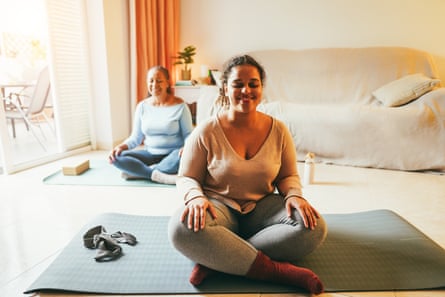Two young women sit cross legged in a lounge.