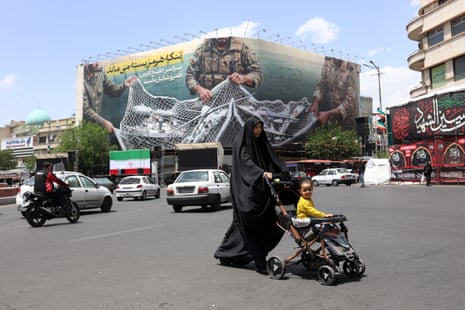 An Iranian woman walks past an anti-US billboard in Tehran carrying a message in Persian saying ‘The strait of Hormuz remains closed’.
