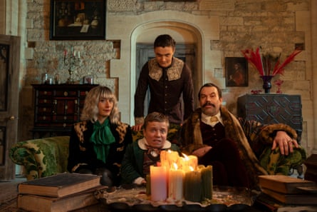 Three people sitting around a table with candles on it, another standing