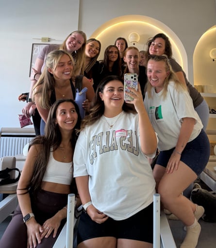 A group of women in gym gear and T-shirts gather for a selfie, all smiling.