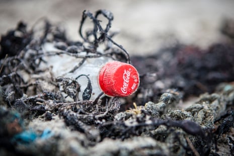 A plastic Coke bottle among seaweed and other flotsam on a beach