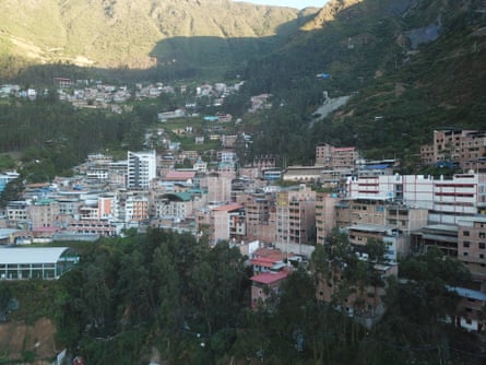 A cluster of buildings, some high rise, sit on the side of a mountain.