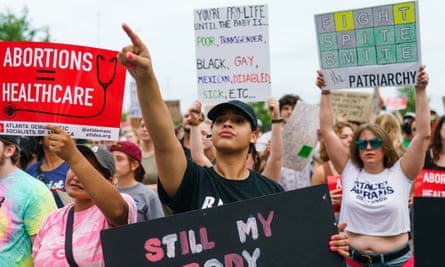 A crowd of women hold signs reading 'Still My Body' and 'Abortions = Healthcare'