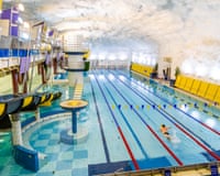 A man swims a lap in a pool with a mottled, white-rock ceiling