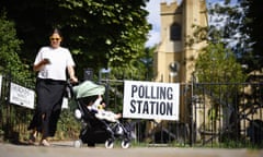 A woman pushing a pram looks at her phone next to a polling station
