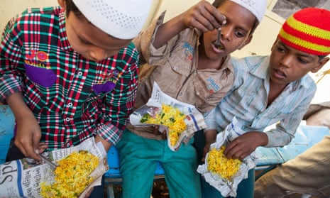 Three boys eat street food in Dhule, Maharashtra, India.