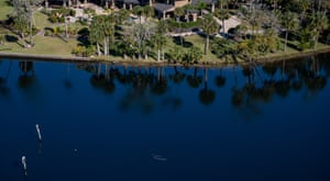 A manatee and her calf swim past a mansion in the shallow water of the Homosassa River.