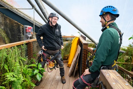 The two men are wearing helmets and one is pulling on a harness