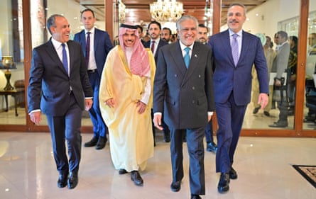 Official from the four countries smile as they walk out of a doorway