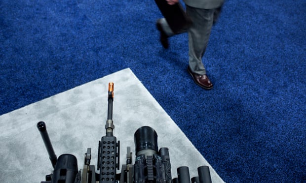 A man walks past an armed robotic system at a trade fair.