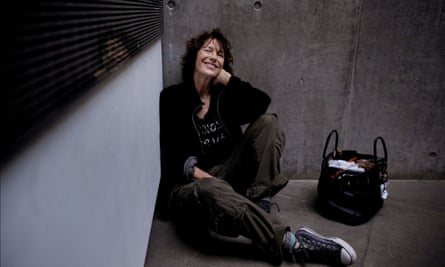 woman smiles while sitting on ground next to bag